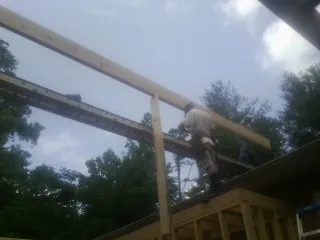 Carpenter setting a ridge beam over a new addition frame — Ice Dam Removal by Roofing Brothers in Islip Terrace