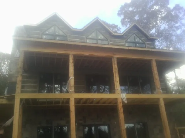 Dormers and porch framing on a large log home under construction — Roof Coating work by our crew in Islip Terrace