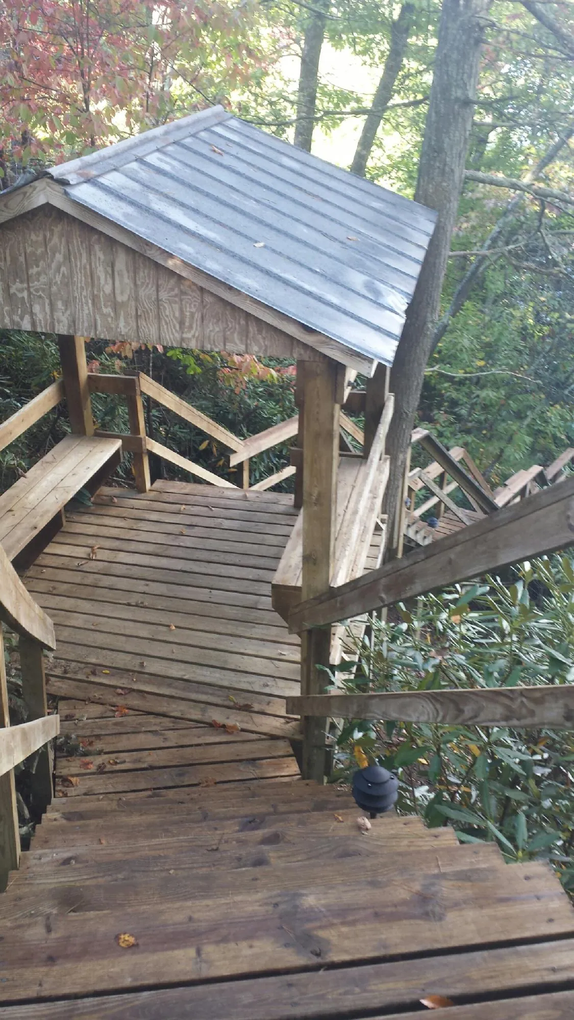 Metal roofed shelter over wooden steps on a wooded walkway — Skylight Repair & Installation work by our crew in Islip Terrace